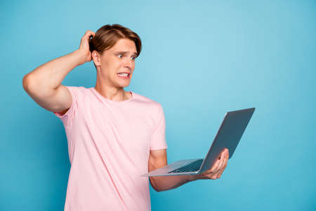 Oops. Profile photo of funny attractive guy holding notebook read error report scratching head have problems wear casual pink t-shirt isolated blue color backgroundの写真素材