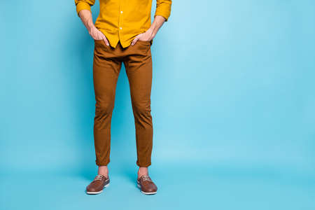 Cropped view of his he young guy, wearing brown pants orange formal casual shirt holding hands in...