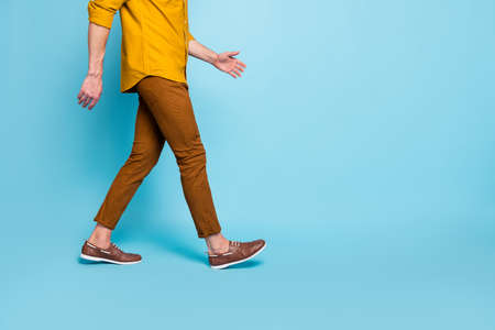 Cropped photo of man going towards empty space in brown shoes, trousers pants trendy trend stylish isolated over blue pastel color backgroundの写真素材