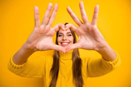 Close up photo of heart cute sweet girl lover make fingers she shows her love sign to boyfriend enjoy 14-february dating wear warm soft jumper isolated over shine color backgroundの写真素材