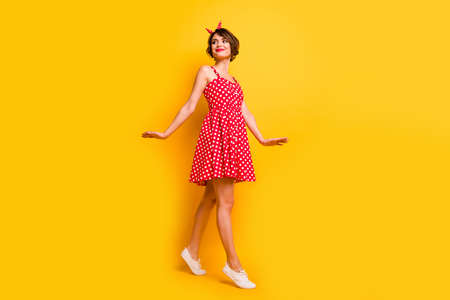 Full size photo of cute pretty sweet girl go walk look copyspace enjoy her spring holiday free time relax wear retro style clothing white footwear isolated over yellow color backgroundの写真素材
