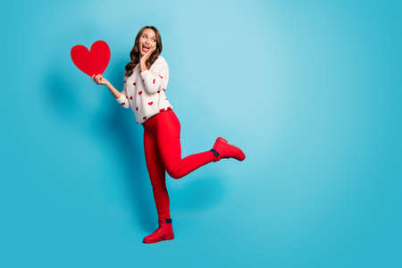 Full length body size view of her she nice attractive lovely cheerful cheery amazed playful girl holding in hand heart having fun isolated on bright vivid shine vibrant blue color backgroundの写真素材