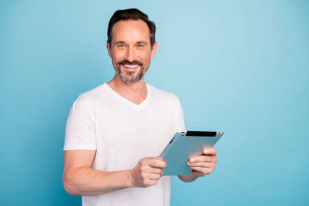 Close-up portrait of nice attractive cheerful cheery guy holding in hands, digital ebook reading...