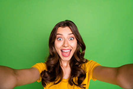 Self-portrait of her she nice attractive lovely cheerful cheery crazy ecstatic, wavy-haired girl having fun free time isolated over bright vivid shine vibrant green color backgroundの写真素材