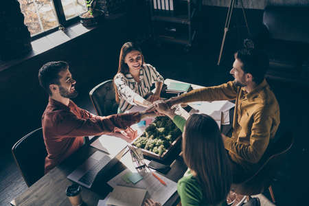 Above high angle view of four nice cheerful experienced professional businesspeople wearing casual...
