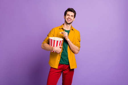 Portrait of positive cheerful guy have free time hold big pop corn box watch tv funny series laugh...