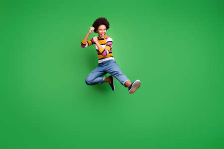 Full length photo of crazy afro american girl hipster jump train kickboxing fight copyspace fall sport kick legs fists wear trendy denim jeans isolated over green color backgroundの写真素材
