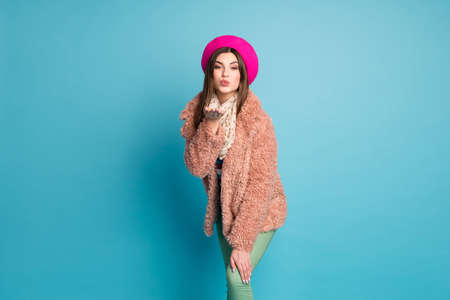 Portrait of attractive girl send air kiss to her boyfriend want attract rich wealthy man she see autumn holidays wear good look outfit green pants trousers isolated blue color backgroundの写真素材