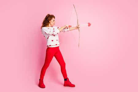 Full length body size profile side view of her she nice attractive lovely fashionable purposeful wavy-haired girl angel shooting arrow dream first date isolated on pink pastel color backgroundの写真素材