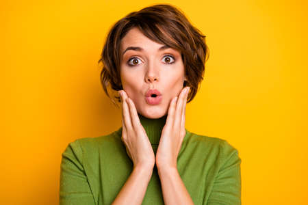 Closeup photo of short hairstyle pretty lady eyes full of fear frightened open mouth listen awful news arms on cheeks wear casual green turtleneck isolated yellow color backgroundの写真素材