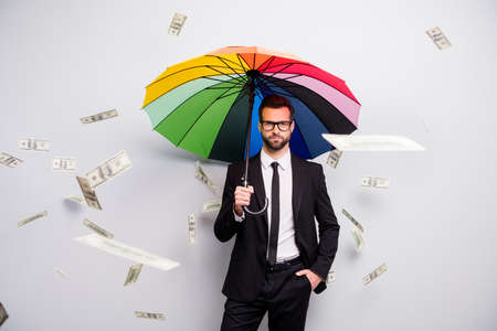 Serious investor manager go walk job hold colorful rainbow parasol shield casback rain money falling flying air wear black tux white shirt pants blazer jacket necktie isolated grey color backgroundの写真素材