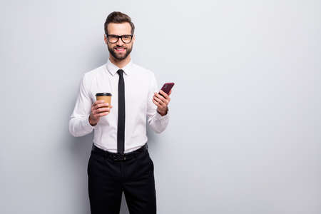 Portrait of positive attorney entrepreneur man hold caffeine beverage mug use cellphone enjoy social media blogging wear white shirt black pants relax isolated grey color backgroundの写真素材