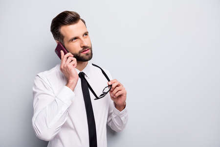 Minded agent freelancer man talk roaming smartphone partners hold spectacles choose decide solution look copyspace wear white shirt black isolated grey color backgroundの写真素材