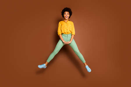 Full length photo of funny dark skin lady jump high up good mood toothy smiling spread legs wear...