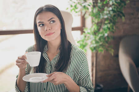 Close-up portrait of her she nice attractive creative pensive lady successful skilled specialist drinking coffee creating strategy at modern industrial brick loft interior style work place stationの写真素材