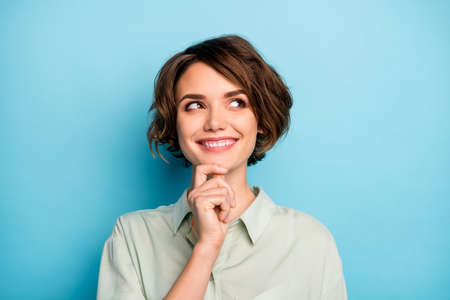 Closeup photo of funny beautiful lady short hairdo look empty space have creative business startup idea arm on chin wear casual green shirt isolated blue color backgroundの写真素材