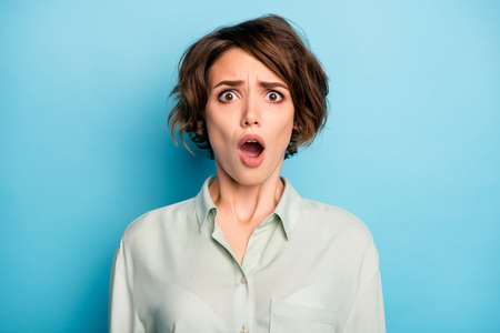 Closeup photo of attractive lady short bob hairstyle not smiling bad mood listen awful news open mouth wear casual formalwear green shirt isolated blue color backgroundの写真素材
