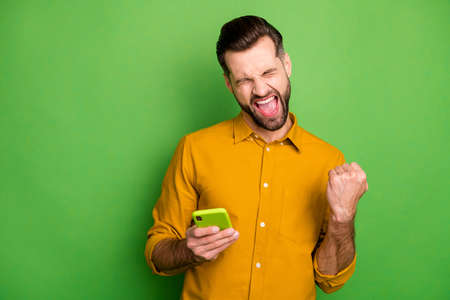 Portrait of his he nice attractive cheerful satisfied guy in formal shirt using cell celebrating...