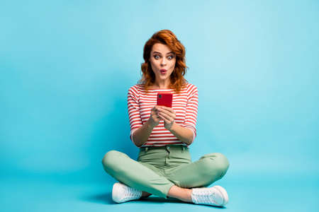 Full size photo excited funny multimedia user woman sit legs crossed use smartphone impressed...