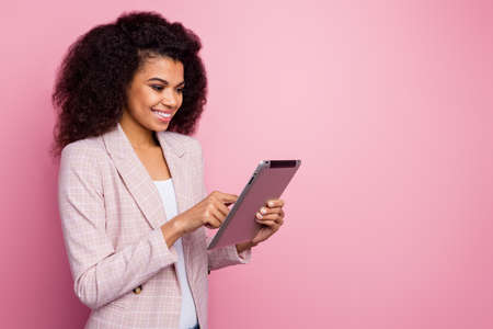 Profile photo of amazing pretty dark skin business lady hold e-book hands successful young professional searching information online wear plaid blazer isolated pastel pink color backgroundの写真素材