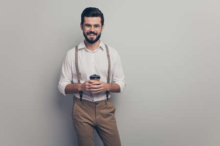 Positive cheerful smart gentleman promoter guy rest relax in cafeteria hold take-away cup with cappuccino wear good look modern clothes isolated over grey color backgroundの写真素材