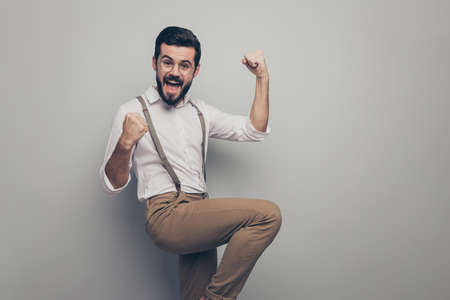 Portrait of crazy funky delighted representative agent collar man get new partnership clients investments raise fists scream yes wear brown modern clothing isolated grey color backgroundの写真素材