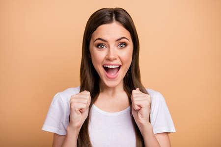 Portrait of ecstatic crazy youth win lottery celebrate her goal raise fists scream yeah wear good looking clothes isolated over beige color backgroundの写真素材