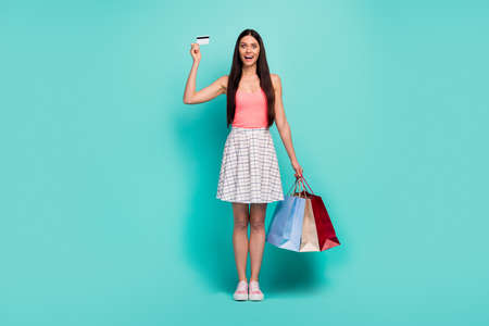 Full size photo crazy astonished girl shopping center client buy use credit card impressed scream wow omg hold bags wear pink tank-top white plaid outfit footwear isolated teal color backgroundの写真素材