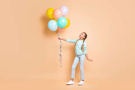 Full length profile photo of beautiful small lady hold many air balloons dreamy look up long braids...