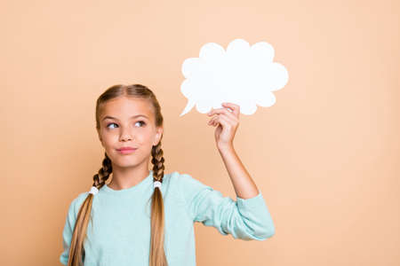 Photo of beautiful little lady holding white empty paper cloud deep thinking look empty space smart school girl wear blue pullover isolated beige pastel color backgroundの写真素材