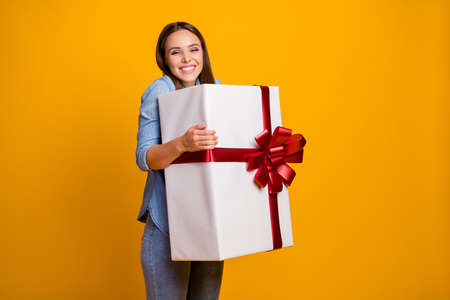 Portrait of energetic crazy girl hold hug get big white gift box with red ribbon enjoy anniversary event party wear good look clothes isolated over shine color backgroundの写真素材