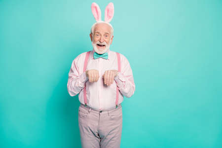 Portrait of amazed excited old man enjoy easter event party imagine he funny funky rabbit fooling with his grandchildren wear pink grey pants trousers isolated over teal color backgroundの写真素材
