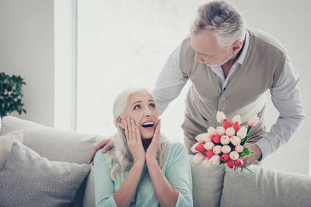 Photo of romance moment aged pair celebrate 8 march holiday giving big red tulips bunch sitting couchの写真素材
