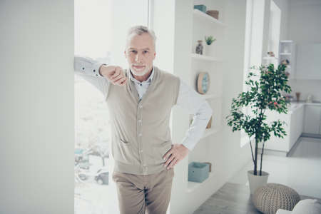 Photo of white haired aged man waiting client for renting house leaning window indoors