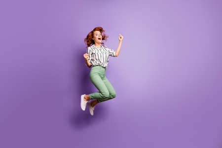 Full size photo of ecstatic woman jump win lottery competition raise fists scream yeah wear good look clothing isolated over purple color backgroundの写真素材