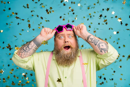 Close-up portrait of his he nice attractive cheerful cheery funky bearded guy putting of glasses flying decorative elements isolated over bright vivid shine vibrant blue color backgroundの写真素材
