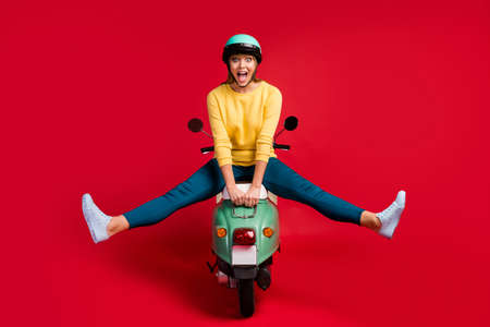 Full length body size view of her she nice attractive lovely crazy amazed cheerful cheery girl sitting on moped fooling having fun time isolated on bright vivid shine vibrant red color backgroundの写真素材