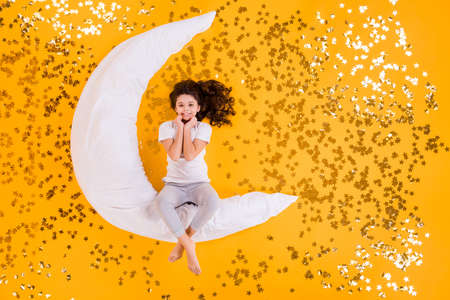 Sweet dreams concept. Full body high angle above flat lay view photo of funny little lady lying floor many sparkling stars moon pillow wear pajama isolated yellow color backgroundの写真素材