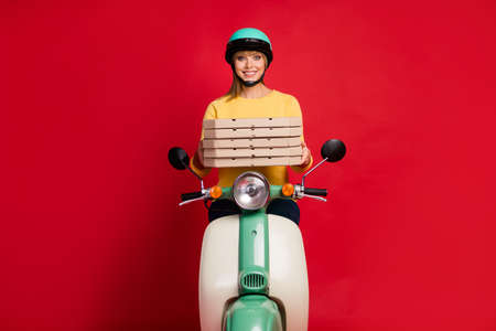 Portrait of her she nice attractive lovely pretty cheerful cheery girl sitting on moped holding in hands pile stack pie dessert isolated on bright vivid shine vibrant red color backgroundの写真素材