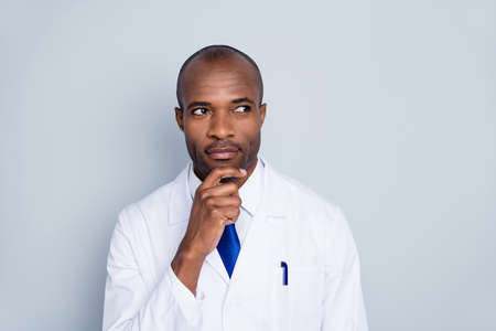 Photo of doctor handsome dark skin guy think of patient virologist diagnosis arm chin experiment look empty space wear white lab coat blue neck tie isolated grey color backgroundの写真素材