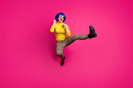 Full length photo of cool funny lady jump high up raise leg fighting exercise wear retro specs yellow turtleneck blue short wig boots leopard pants isolated bright pink color backgroundの写真素材