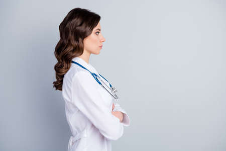 Profile photo of attractive family doc lady consultation virology scientific meeting listen colleagues arms crossed look empty space wear lab coat stethoscope isolated grey color backgroundの写真素材