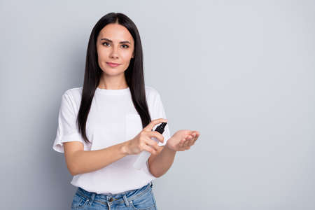 Portrait of serious strict girl advertise people wash hands use sanitizer to kill germs wear trendy denim jeans isolated over gray color backgroundの写真素材