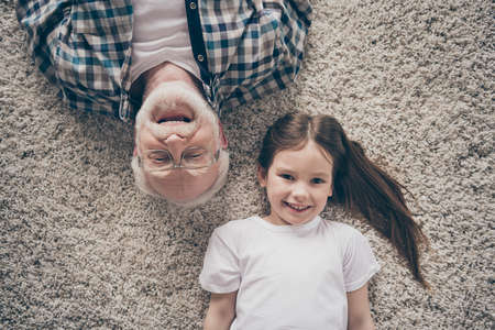 High angle top above photo of two people grandpa little granddaughter lying floor cozy fluffy carpet...