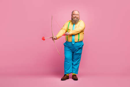 Full length body size view of his he nice funky dreamy glad bearded guy shooting amorous arrows aim goal meeting arrangement isolated over pink pastel color backgroundの写真素材