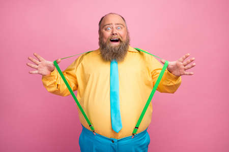 Portrait of his he nice funky carefree amazed bearded positive glad guy pulling suspenders having fun good mood isolated over pink pastel color backgroundの写真素材
