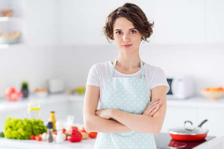 Photo of beautiful bobbed hairdo housewife holding arms crossed enjoy morning cooking tasty dinner family meeting wear apron t-shirt stand modern kitchen indoorsの写真素材