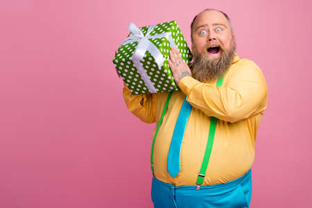 Portrait of his he nice funky curious bearded positive glad guy holding in hands dotted giftbox...