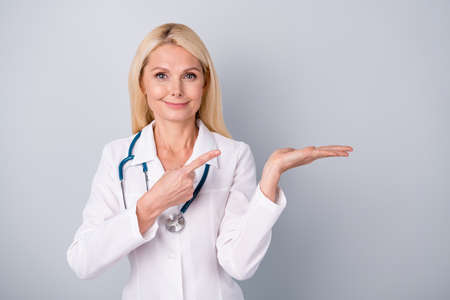 Positive emotion doctor woman hold hand point index finger demonstrate medication protection isolated over gray color backgroundの写真素材