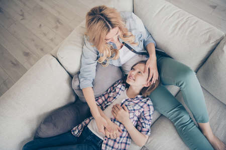 Hih angle above view photo of charming blond mommy daughter two ladies relaxing lying comfy couch hold arms overjoyed stay home quarantine time spend weekend together living room indoorsの写真素材
